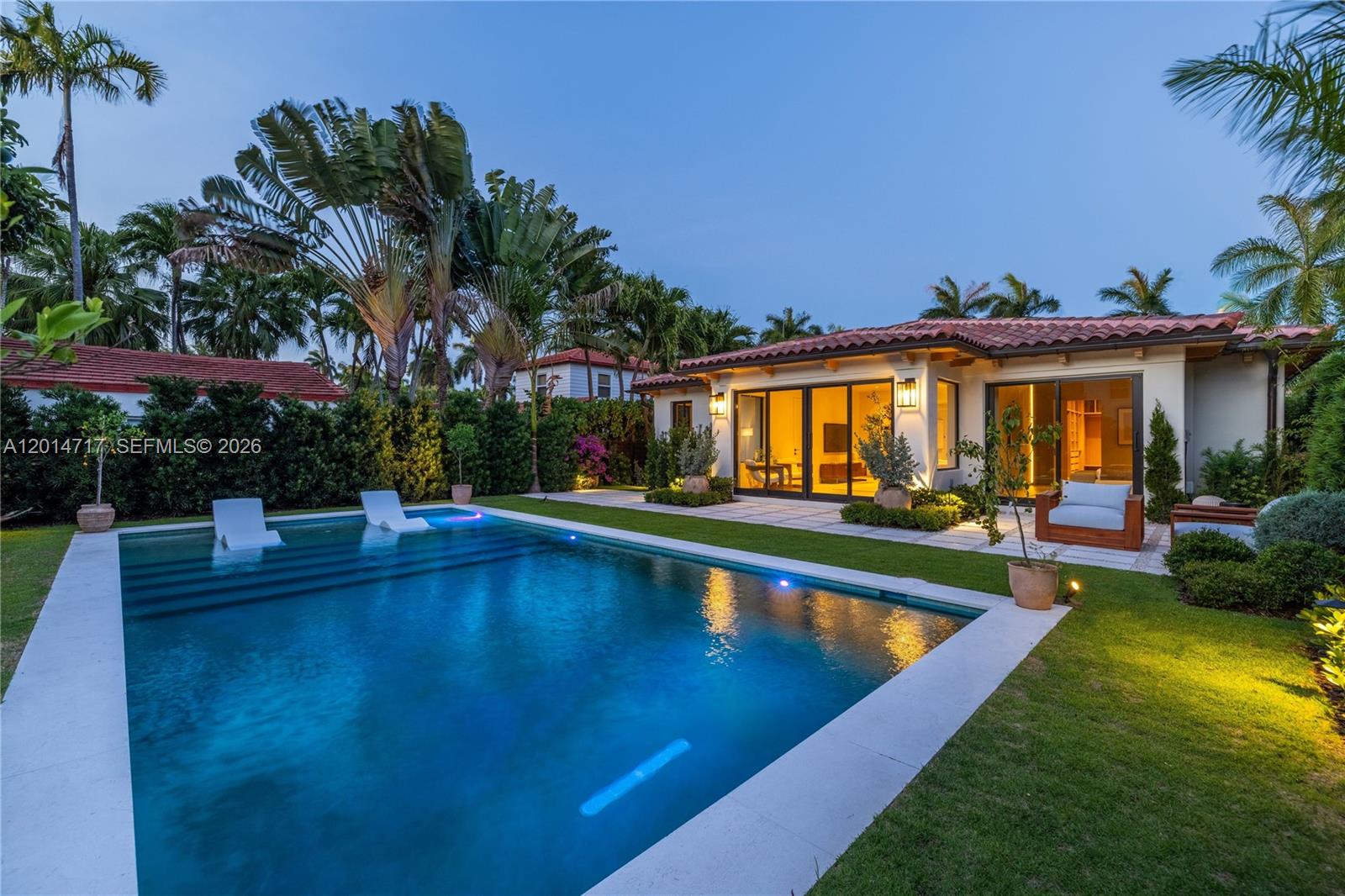 A backyard features a swimming pool with lounge chairs and a house with sliding doors — 4430 Royal Palm Ave, Miami Beach FL 33140, MIAMI BEACH, FL