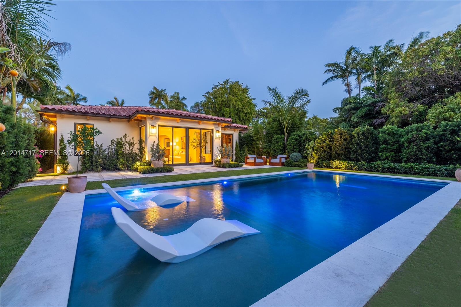 A swimming pool with two lounge chairs sits in front of a house with a patio — 4430 Royal Palm Ave, Miami Beach FL 33140, MIAMI BEACH, FL