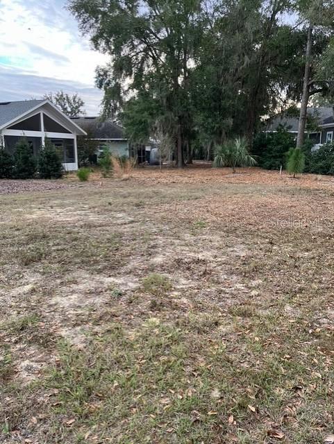 A grassy, partially cleared lot sits in front of a house with a screened porch — 2660 NW 47TH TERRACE, GAINESVILLE, FL