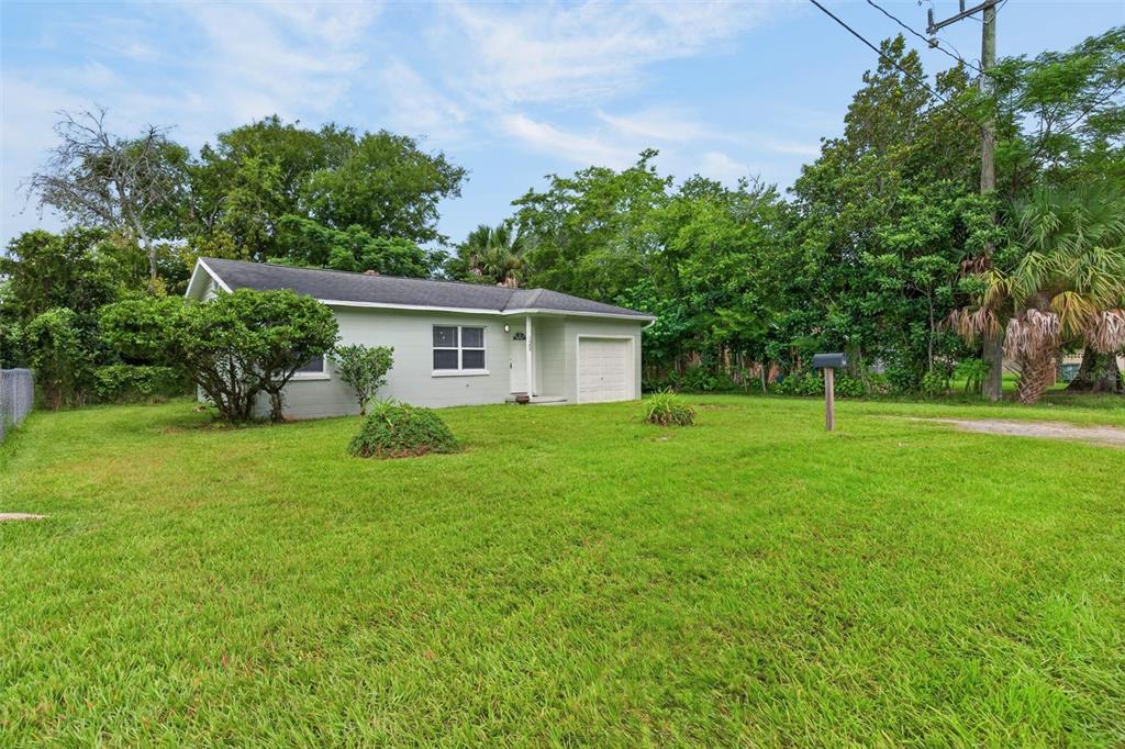 A single-story house with a light green exterior, a small garage, and a large front lawn — 126 HARNEY STREET, DAYTONA BEACH, FL