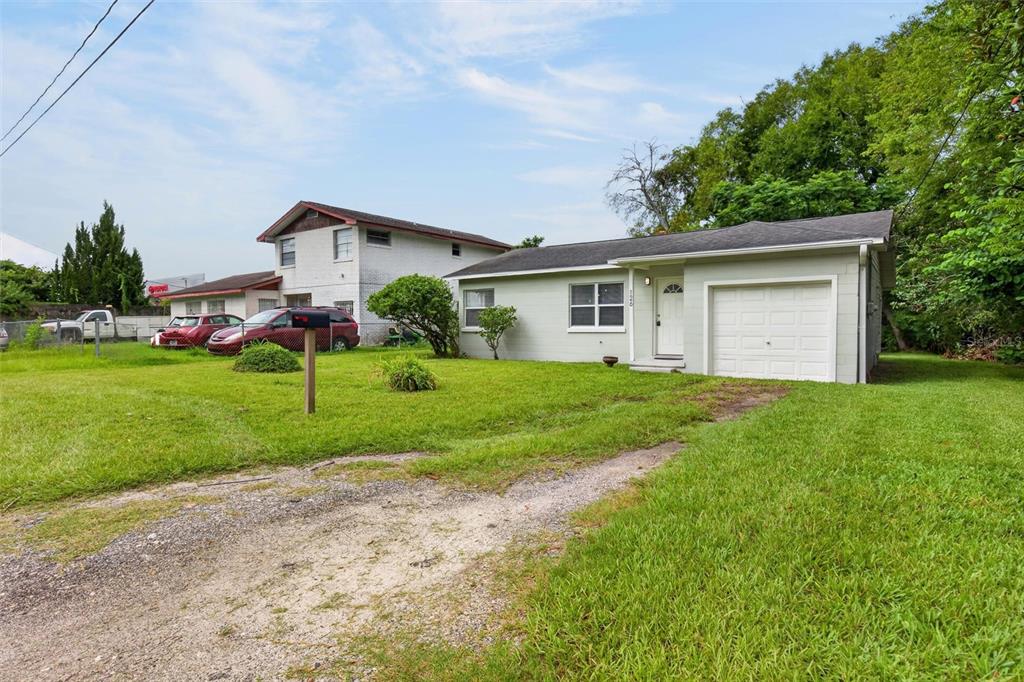 A single-story house with a light green exterior, a white garage door, and a gravel driveway — 126 HARNEY STREET, DAYTONA BEACH, FL