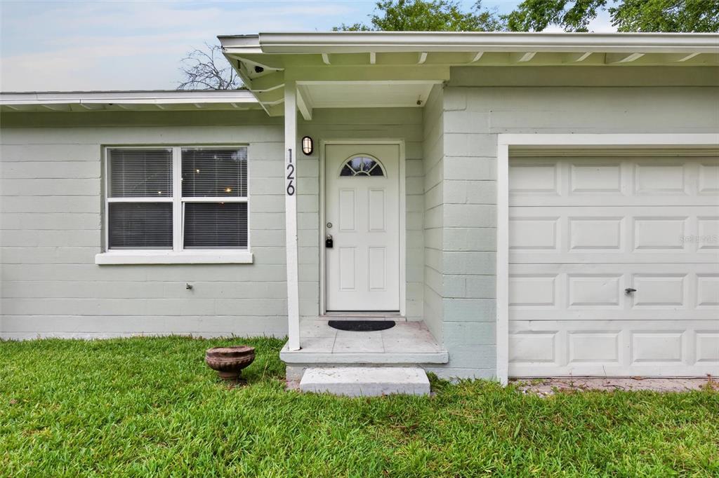 The exterior of a light green house features a white front door and garage door — 126 HARNEY STREET, DAYTONA BEACH, FL