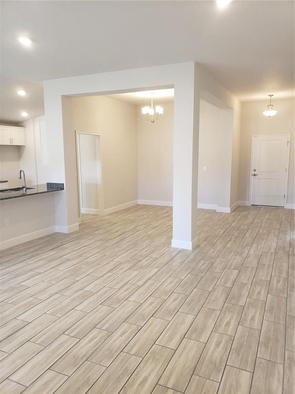An open-concept living area features light wood-look tile flooring and a central support pillar — 4866 SUTHERLAND STREET Lot 62, SPRING HILL, FL