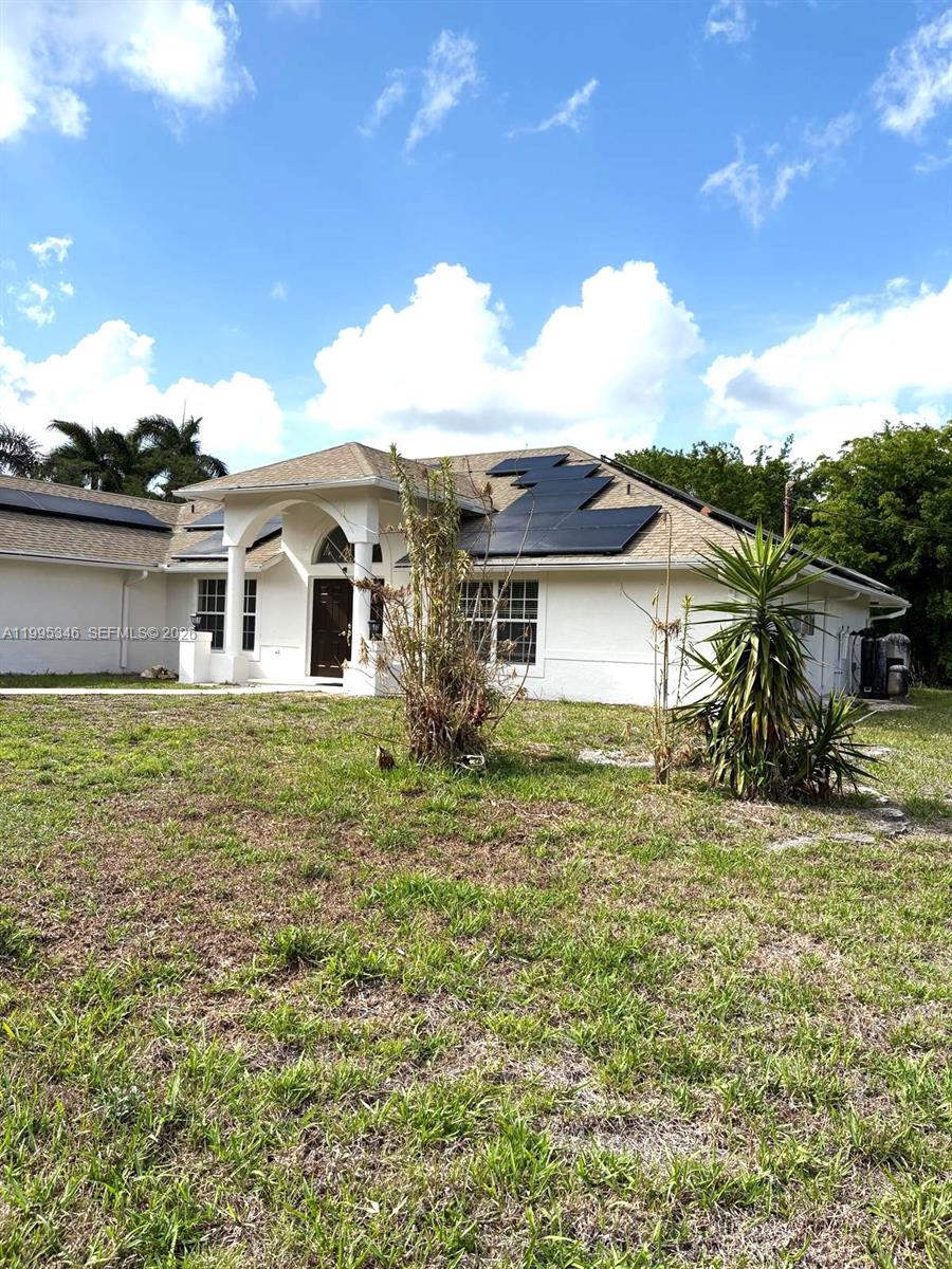 A single-story house with a white exterior, a covered entryway, and solar panels on the roof — 16613 N 61st Pl N, Westlake FL 33470, WESTLAKE, FL