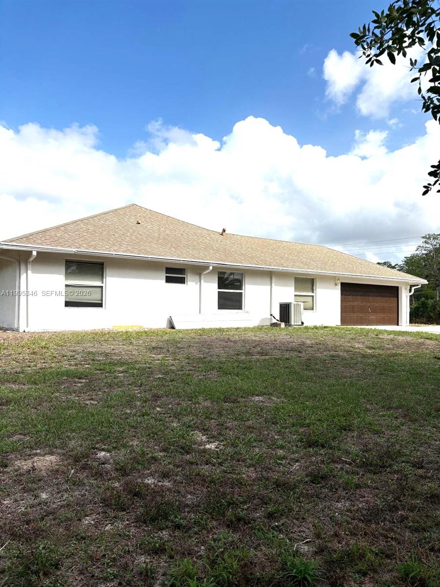 The rear exterior of a single-story house features a brown garage door and lawn — 16613 N 61st Pl N, Westlake FL 33470, WESTLAKE, FL
