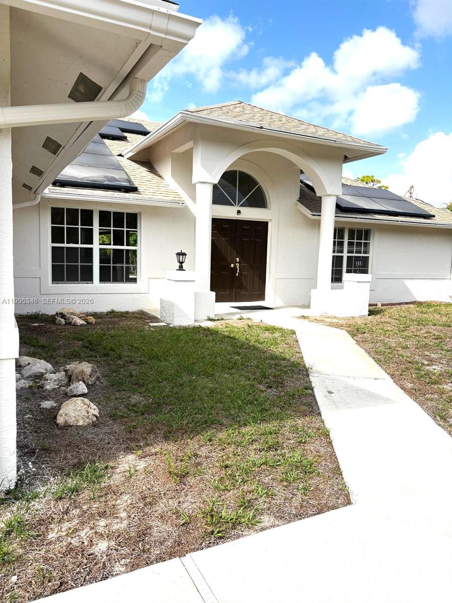 A white stucco house features a covered entryway with columns and dark double doors — 16613 N 61st Pl N, Westlake FL 33470, WESTLAKE, FL