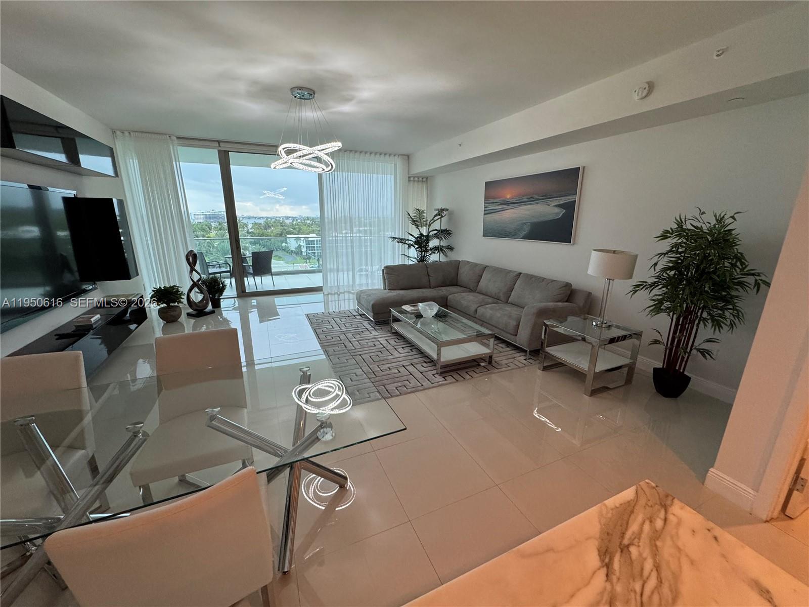 A modern living and dining area features tile floors, a sectional sofa, and floor-to-ceiling windows — 10203 Collins Ave # 604, Bal Harbour FL 33154, BAL HARBOUR, FL