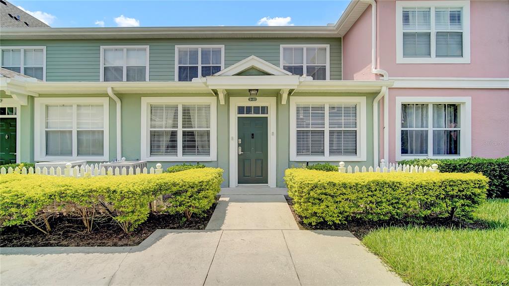 A two-story townhouse exterior with green siding, a dark green front door, and manicured hedges — 4009 VENETIAN BAY DRIVE UNIT 103, KISSIMMEE, FL
