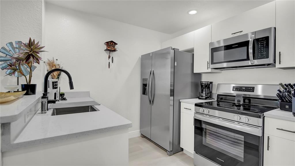 A kitchen features stainless steel appliances, white cabinets, and a sink on a peninsula counter — 4009 VENETIAN BAY DRIVE UNIT 103, KISSIMMEE, FL