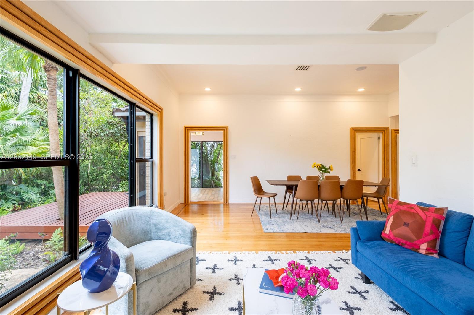 A bright living and dining area features hardwood floors, large windows, and outdoor deck views — 4230 Royal Palm Ave, Miami Beach FL 33140, MIAMI BEACH, FL