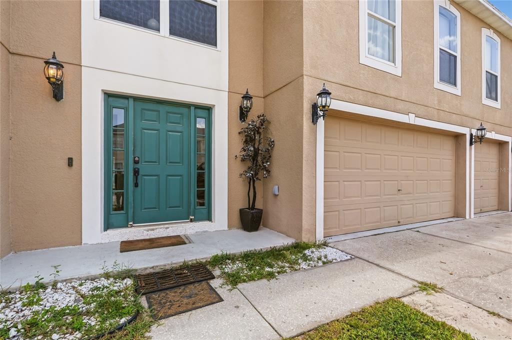 The exterior of a two-story townhouse features a teal front door and a beige garage — 177 FISH HAWK DRIVE, WINTER HAVEN, FL