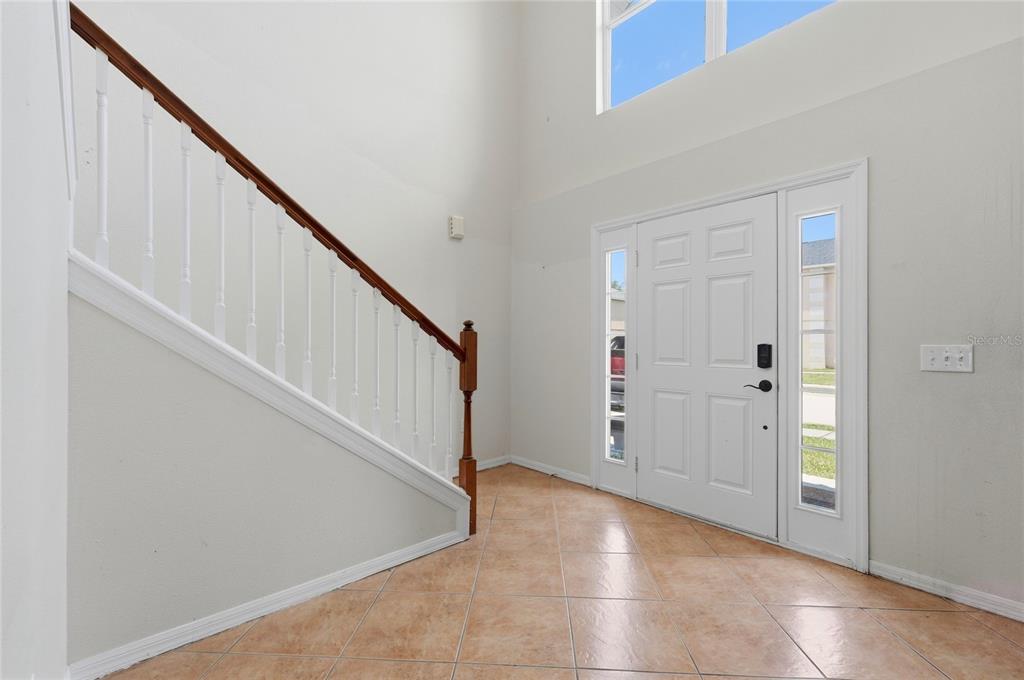 A bright entryway features a tiled floor, a staircase with a wooden railing, and a door — 177 FISH HAWK DRIVE, WINTER HAVEN, FL