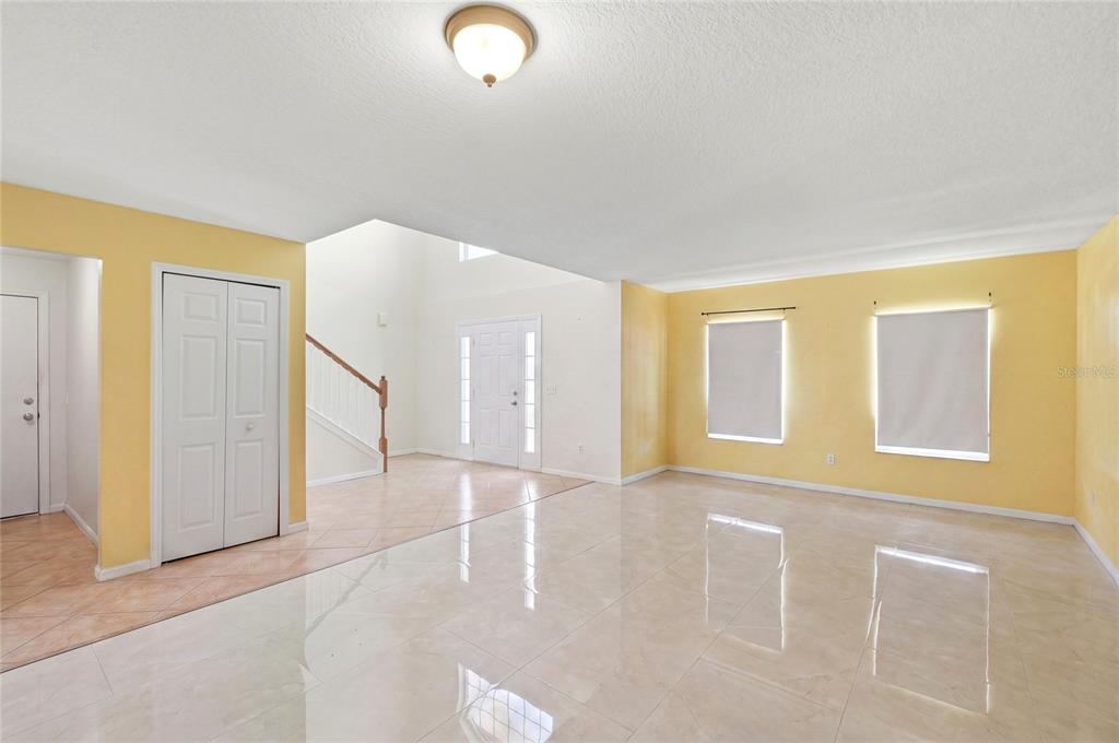 A bright, open living area features yellow walls, light-colored tile flooring, and a staircase — 177 FISH HAWK DRIVE, WINTER HAVEN, FL