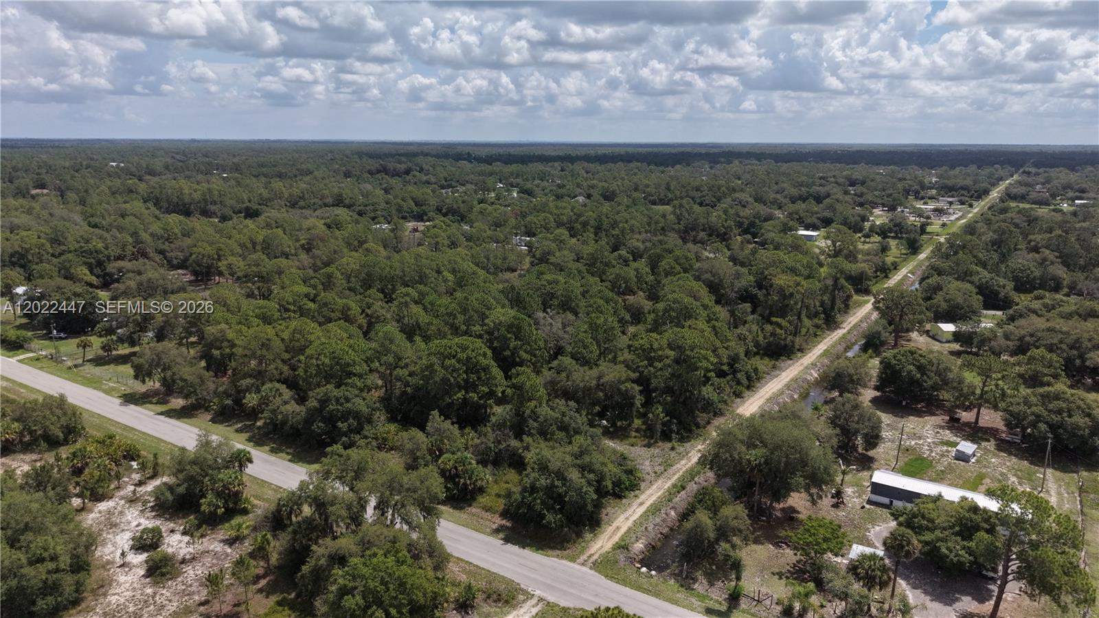 An aerial view shows a paved road bordering a large, wooded plot of land — 375 S Mayoral St, Clewiston FL 33440, CLEWISTON, FL