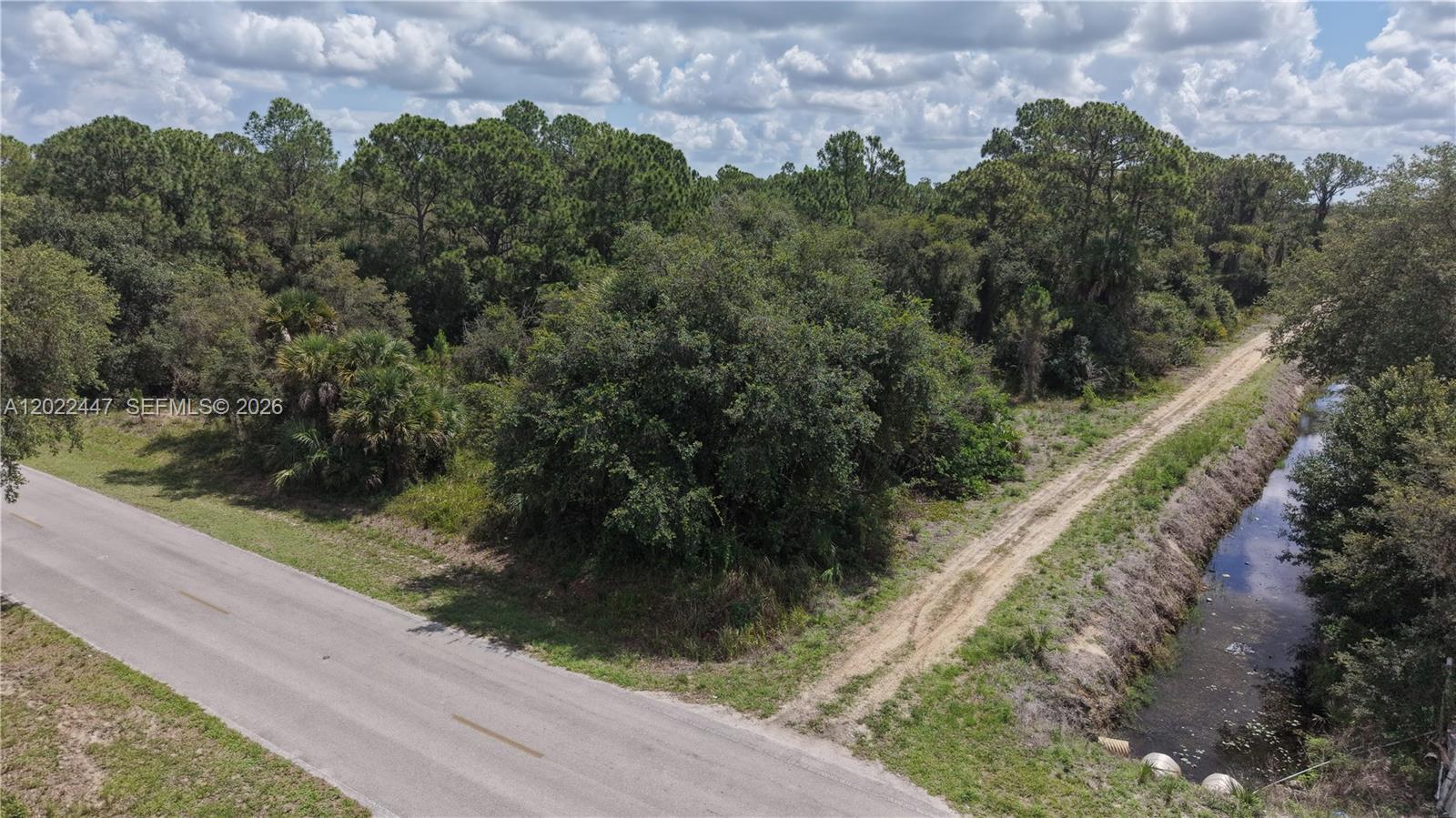 An aerial view shows a paved road, a dirt path, a canal, and dense vegetation — 375 S Mayoral St, Clewiston FL 33440, CLEWISTON, FL
