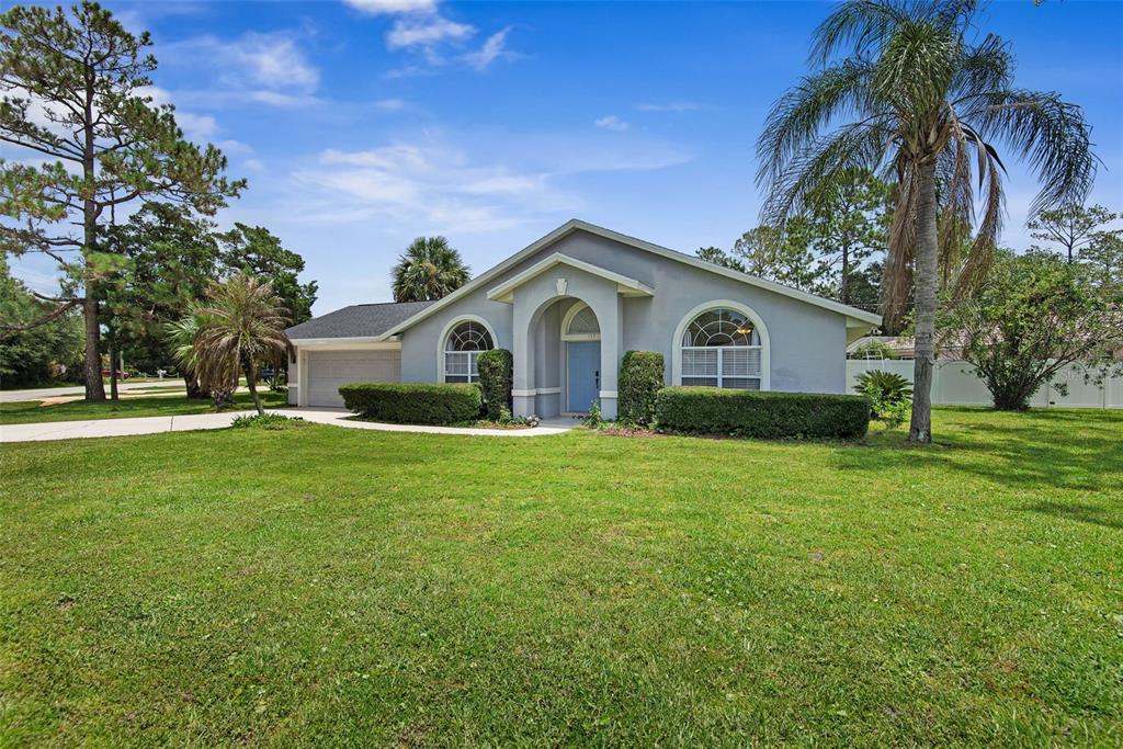 A single-story gray house with a blue front door and a large front lawn — 113 WHIPPOORWILL DRIVE, PALM COAST, FL