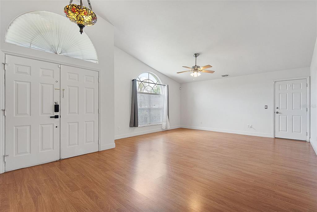 An empty room with wood-look flooring, white walls, a ceiling fan, and arched windows — 113 WHIPPOORWILL DRIVE, PALM COAST, FL