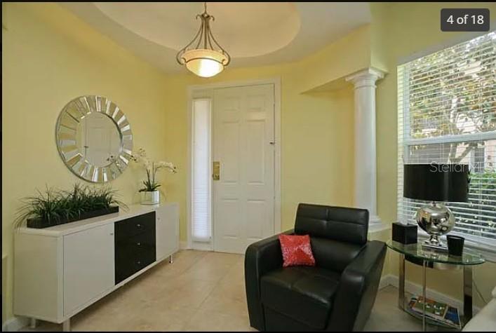 A bright living room features a white sofa, tiled floors, and two decorative columns — 5514 46TH COURT W, BRADENTON, FL