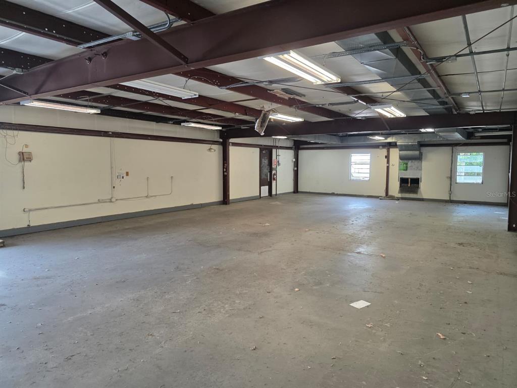 An empty industrial warehouse space features exposed steel beams, concrete floors, and fluorescent lighting — 3603 W BEARSS AVENUE, TAMPA, FL
