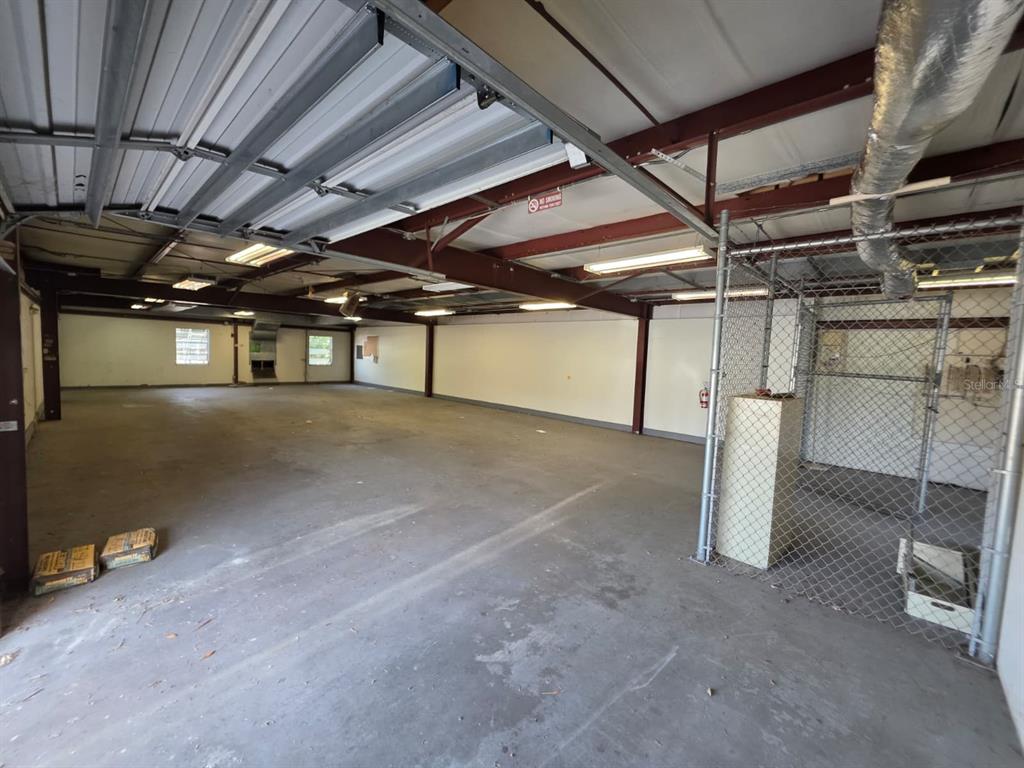 An open warehouse space features a concrete floor, exposed steel beams, and a chain-link enclosure — 3603 W BEARSS AVENUE, TAMPA, FL
