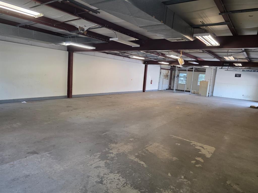 An empty industrial warehouse space features concrete floors, exposed ceiling beams, and overhead lighting — 3603 W BEARSS AVENUE, TAMPA, FL