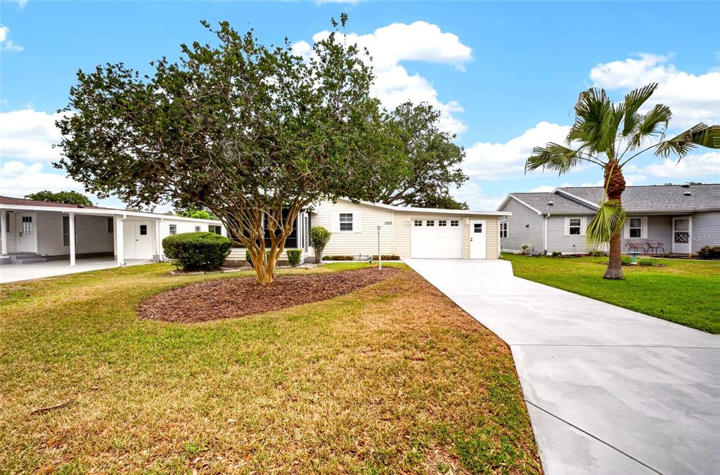 A single-story house with a white exterior, a concrete driveway, and a large front tree — 1222 ZAPATA PLACE, LADY LAKE, FL