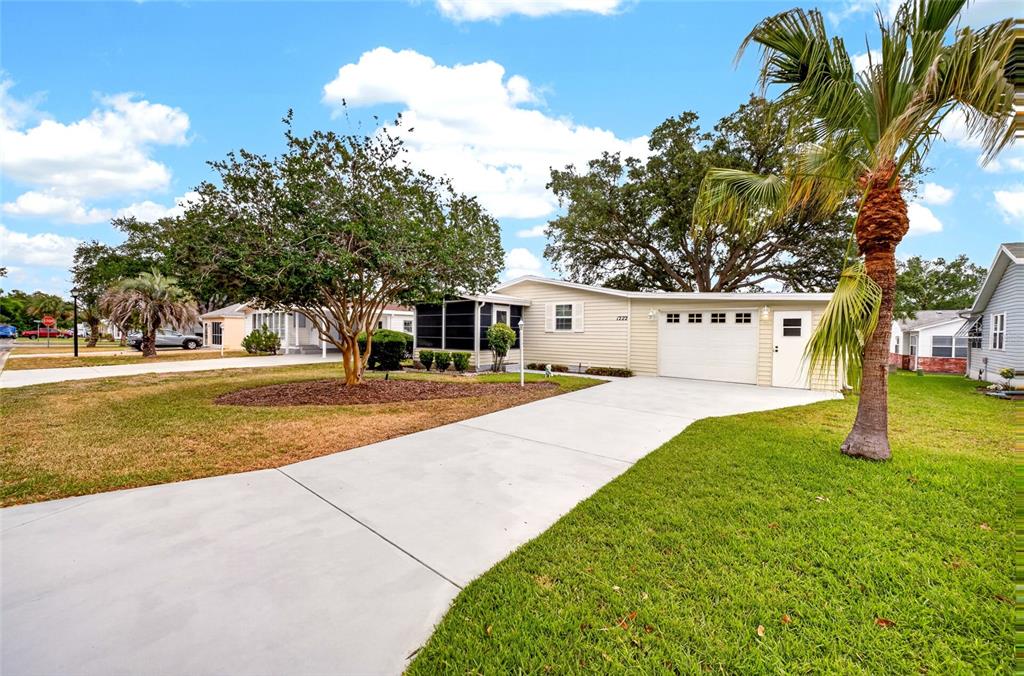 A single-story house with light siding, a white garage door, and a concrete driveway — 1222 ZAPATA PLACE, LADY LAKE, FL