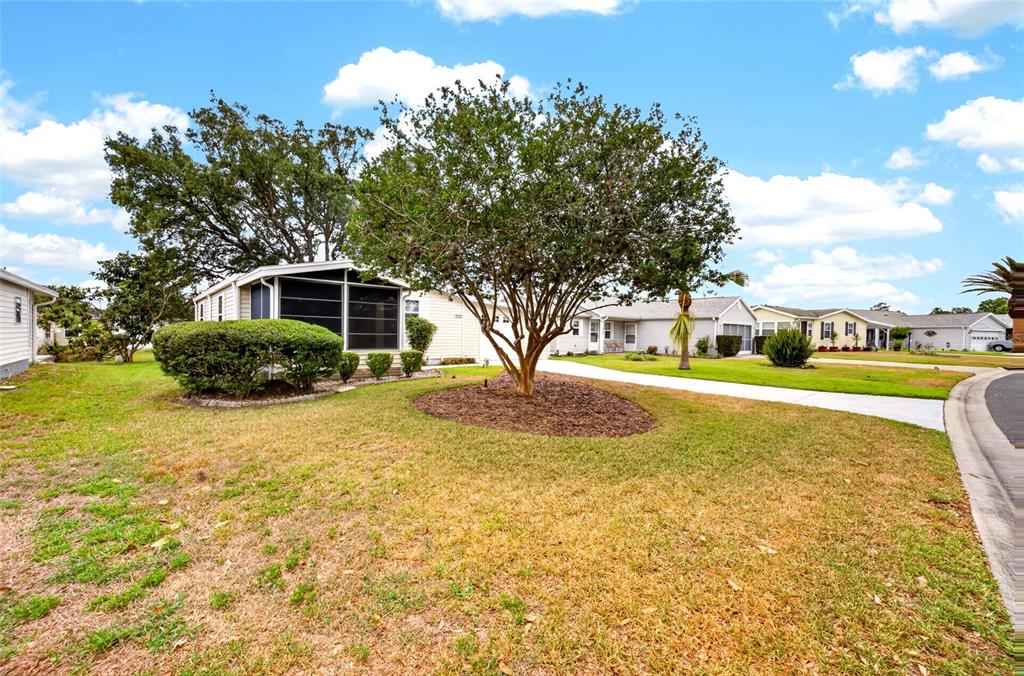 A single-story house with a screened-in porch sits on a lawn with a large tree — 1222 ZAPATA PLACE, LADY LAKE, FL