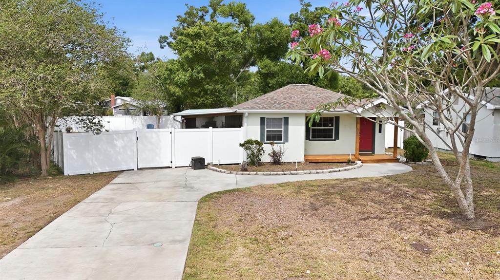 A single-story house with a white exterior, red front door, and a white privacy fence — 4608 46TH STREET N, ST PETERSBURG, FL