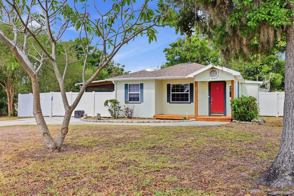 A light-colored single-story house with a bright red front door and a white privacy fence — 4608 46TH STREET N, ST PETERSBURG, FL