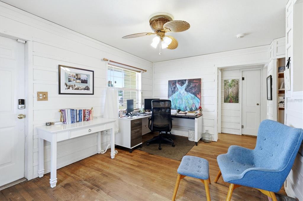 A home office with white shiplap walls, hardwood floors, a desk, and a blue chair — 4608 46TH STREET N, ST PETERSBURG, FL