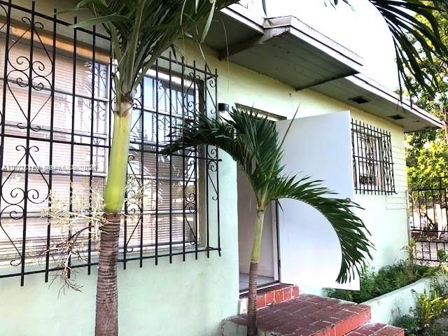 A light green house exterior features a white door, security bars, and two palm trees — 1321 NW 28th St, Miami FL 33142, MIAMI, FL