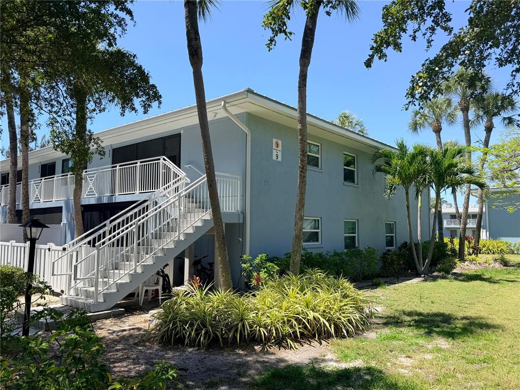 A two-story light blue apartment building features an exterior staircase leading to a second-floor balcony — 600 MANATEE AVENUE UNIT 227, BRADENTON BEACH, FL