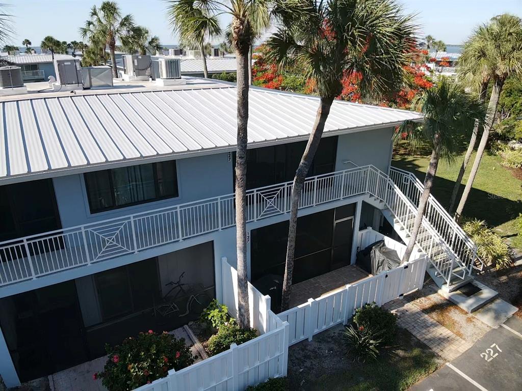 An aerial view of a two-story building with a metal roof and white balcony railings — 600 MANATEE AVENUE UNIT 227, BRADENTON BEACH, FL