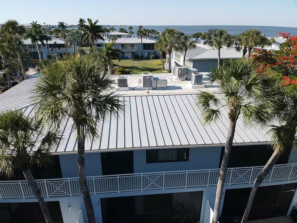 An elevated exterior view of a multi-story building with a metal roof and palm trees — 600 MANATEE AVENUE UNIT 227, BRADENTON BEACH, FL