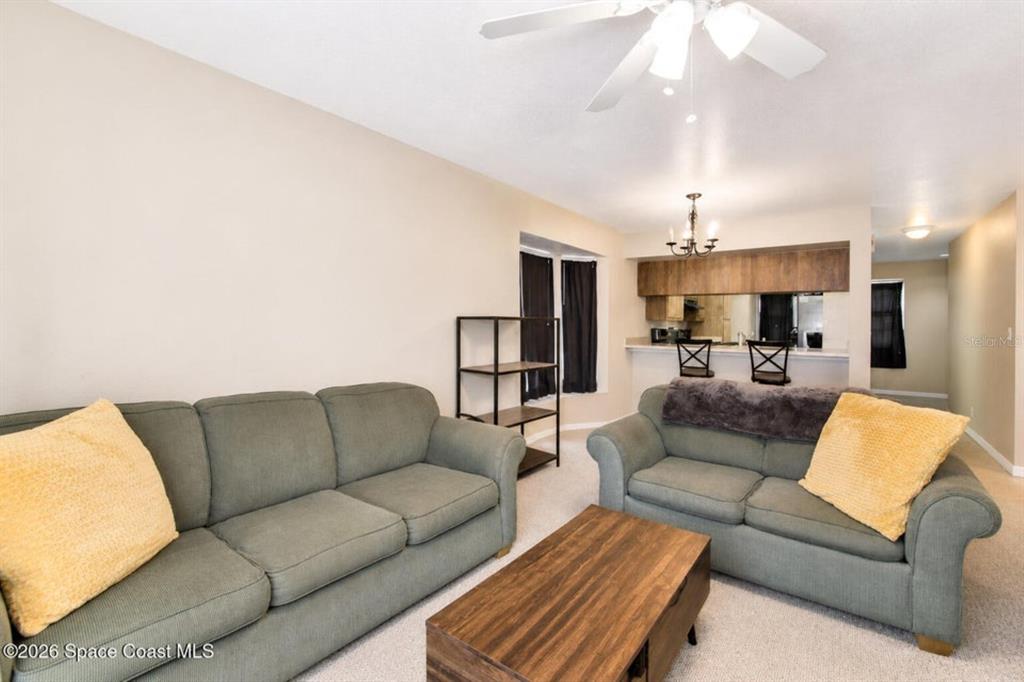 A living room features two green sofas, a wooden coffee table, and a breakfast bar — 1795 HARRISON STREET UNIT 213, TITUSVILLE, FL