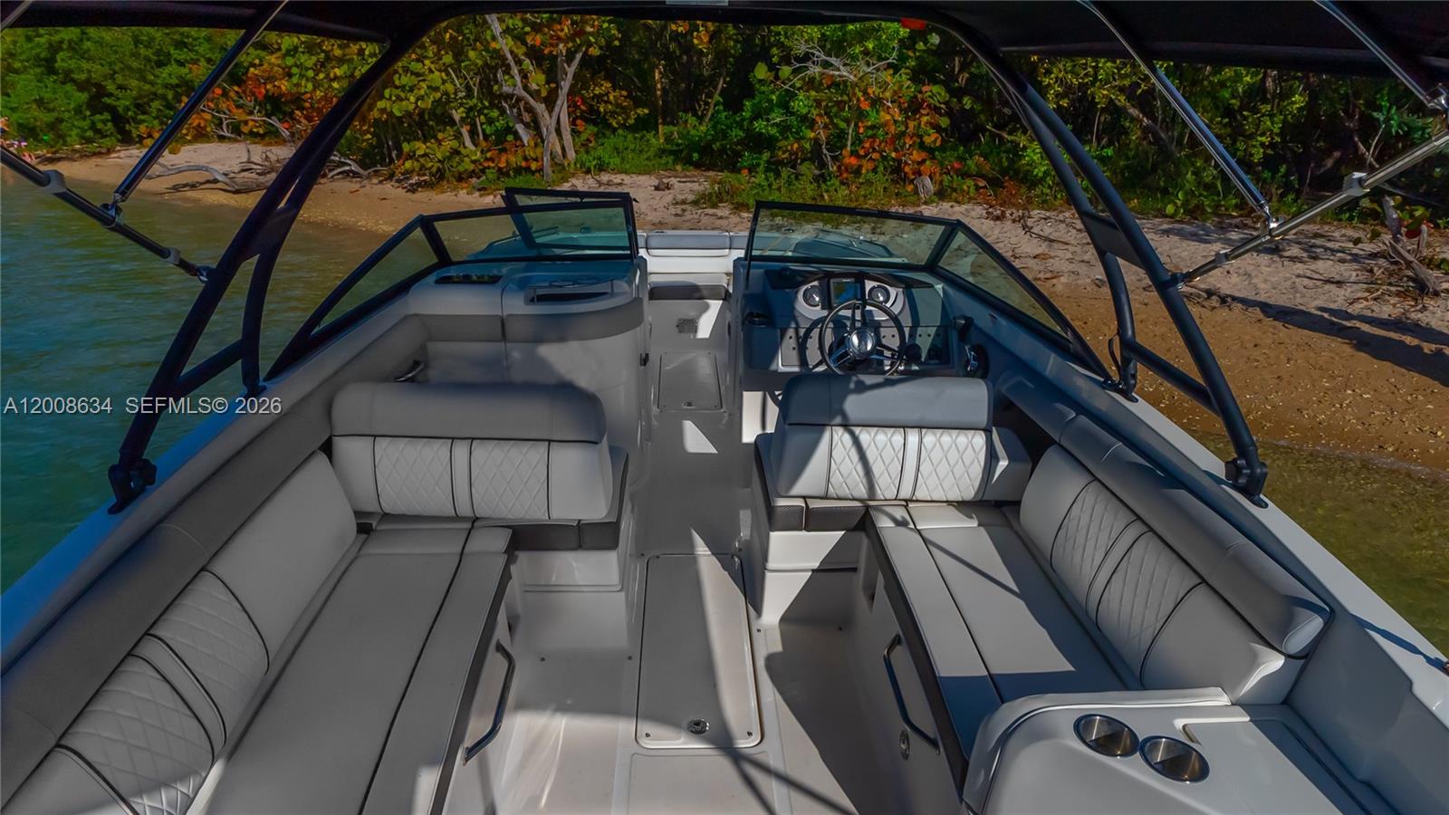 The interior of a motorboat features gray upholstered seating, a steering console, and a bimini top — 910 West Ave, Miami Beach FL 33139, MIAMI BEACH, FL