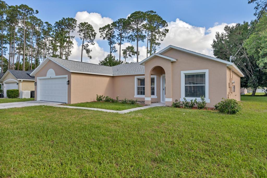 A single-story tan house with a two-car garage and a front-facing arched entryway — 62 BELVEDERE LANE, PALM COAST, FL
