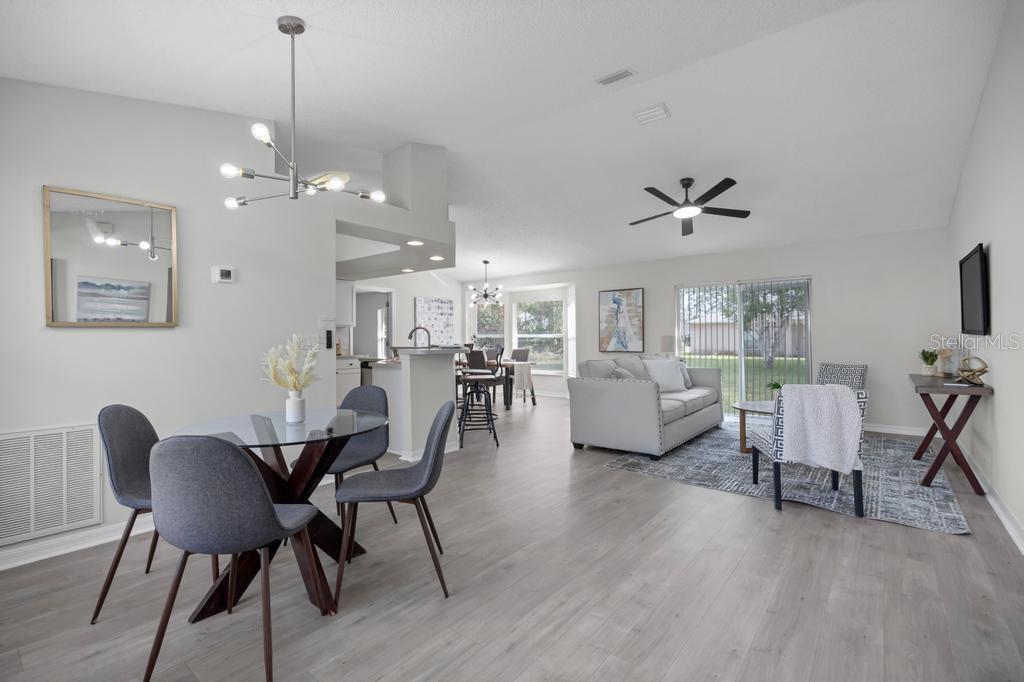 An open-concept living and dining area features light wood flooring, neutral walls, and modern lighting — 62 BELVEDERE LANE, PALM COAST, FL