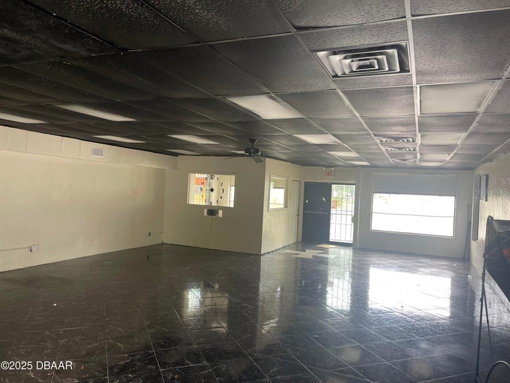 An empty commercial space features a black drop ceiling, dark tiled floors, and white walls — 833 MASON AVENUE, DAYTONA BEACH, FL