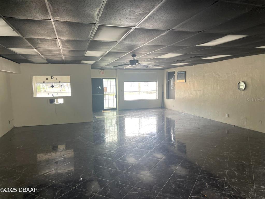 An empty commercial space features a black drop ceiling, dark tiled floors, and white walls — 833 MASON AVENUE, DAYTONA BEACH, FL