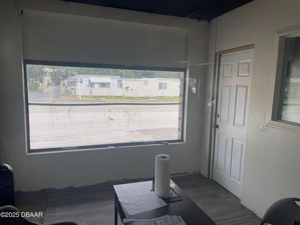 An interior room features a large window, a white door, and gray wood-look flooring — 833 MASON AVENUE, DAYTONA BEACH, FL