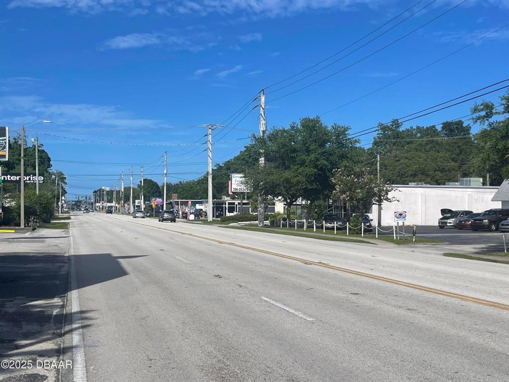A view of a multi-lane road with utility poles, trees, and commercial buildings on both sides — 833 MASON AVENUE, DAYTONA BEACH, FL