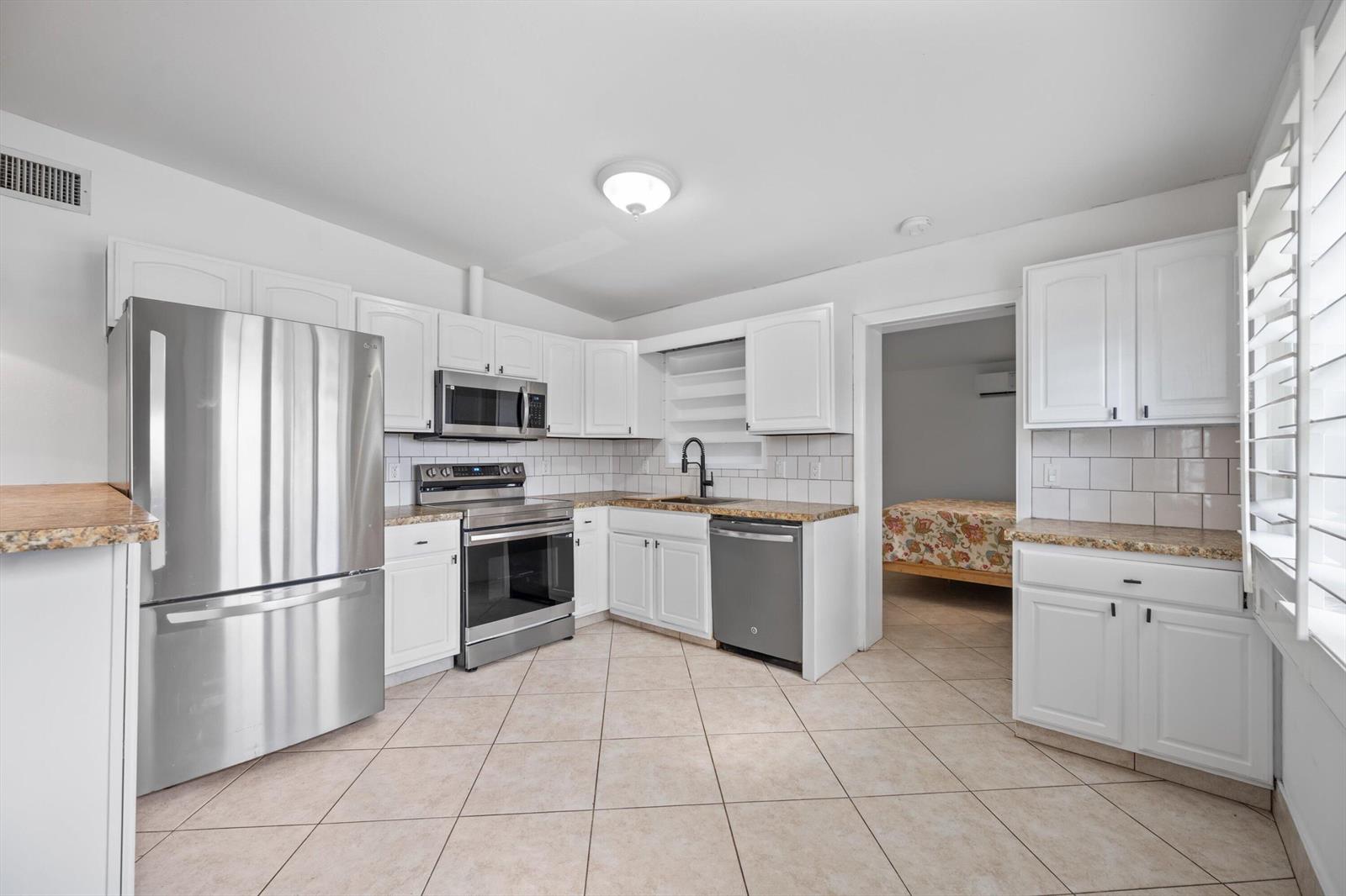 A kitchen with white cabinets, stainless steel appliances, granite countertops, and light-colored tile flooring — 2179 Pepper Road, West Palm Beach FL 33415, WEST PALM BEACH, FL