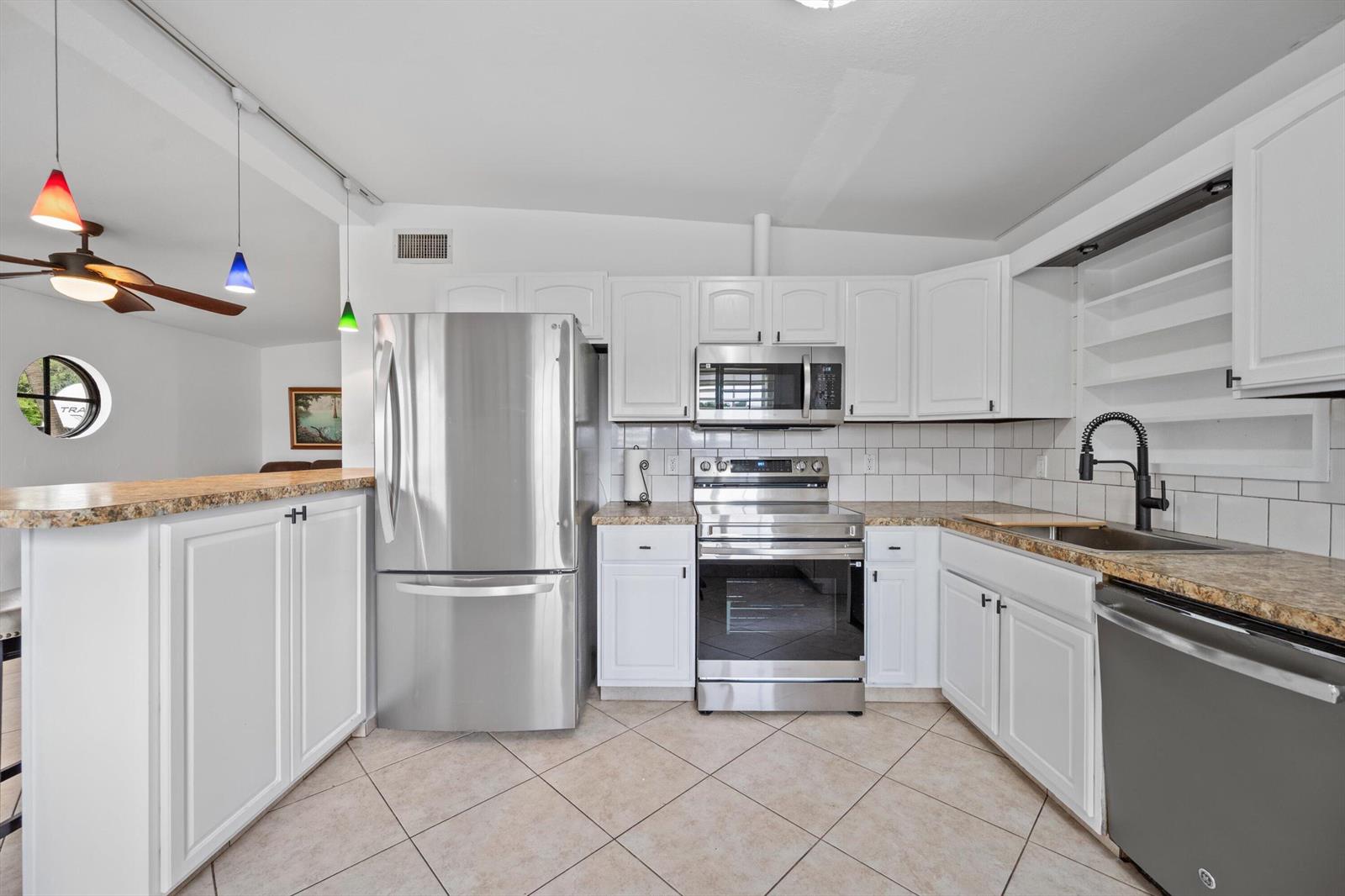 A kitchen features white cabinets, stainless steel appliances, granite countertops, and a tiled floor — 2179 Pepper Road, West Palm Beach FL 33415, WEST PALM BEACH, FL