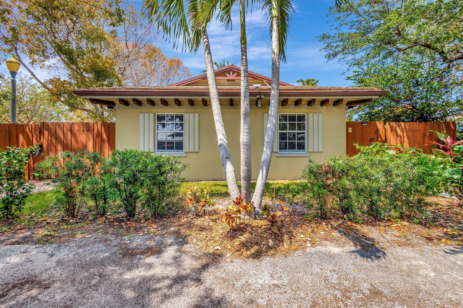 A single-story house with a tan exterior, two windows, and palm trees in the front yard — 227 NE 12th Street # 1, Delray Beach FL 33444, DELRAY BEACH, FL