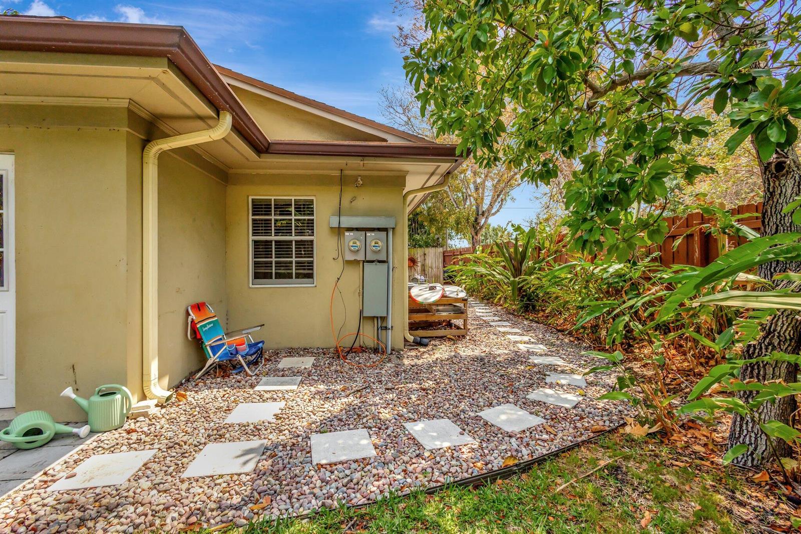 A gravel side yard with a stone path, a folding chair, and utility boxes — 227 NE 12th Street # 1, Delray Beach FL 33444, DELRAY BEACH, FL