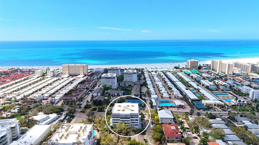 An aerial view shows a multi-story apartment building circled in a residential coastal area — 1200 EAST PEPPERTREE LANE UNIT 302, SARASOTA, FL
