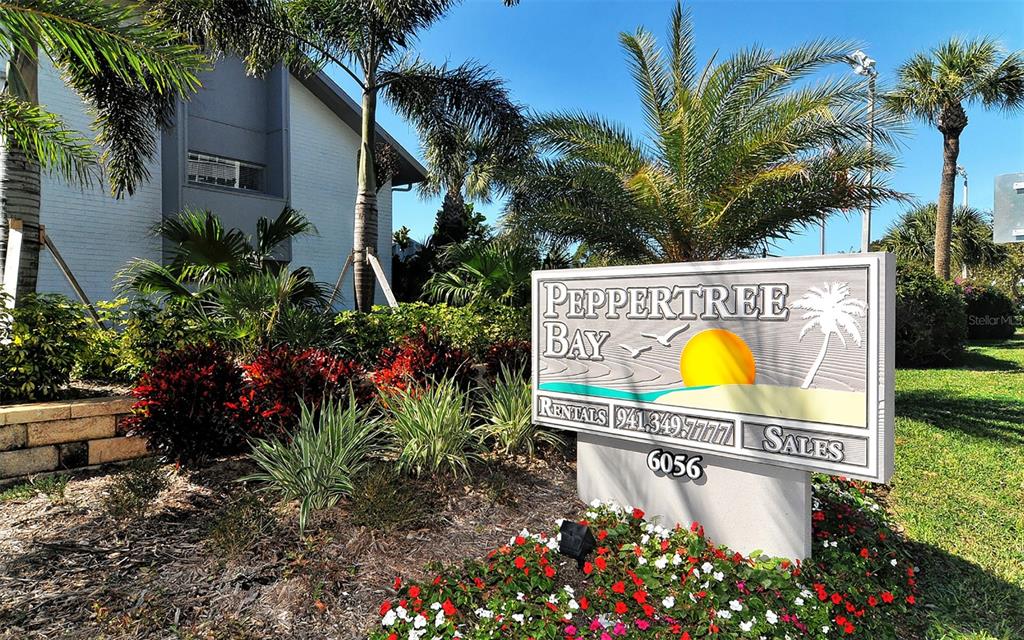 A sign for Peppertree Bay stands in a landscaped garden in front of a building — 1200 EAST PEPPERTREE LANE UNIT 302, SARASOTA, FL