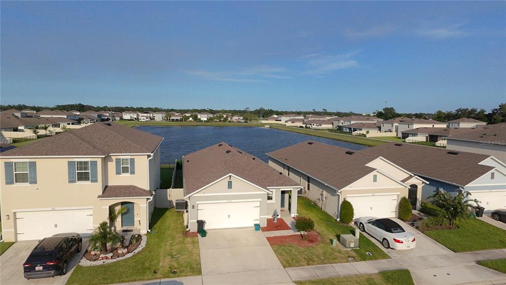 An aerial view shows three suburban houses with driveways facing a large retention pond — 3925 ANGOLA LANE, SANFORD, FL